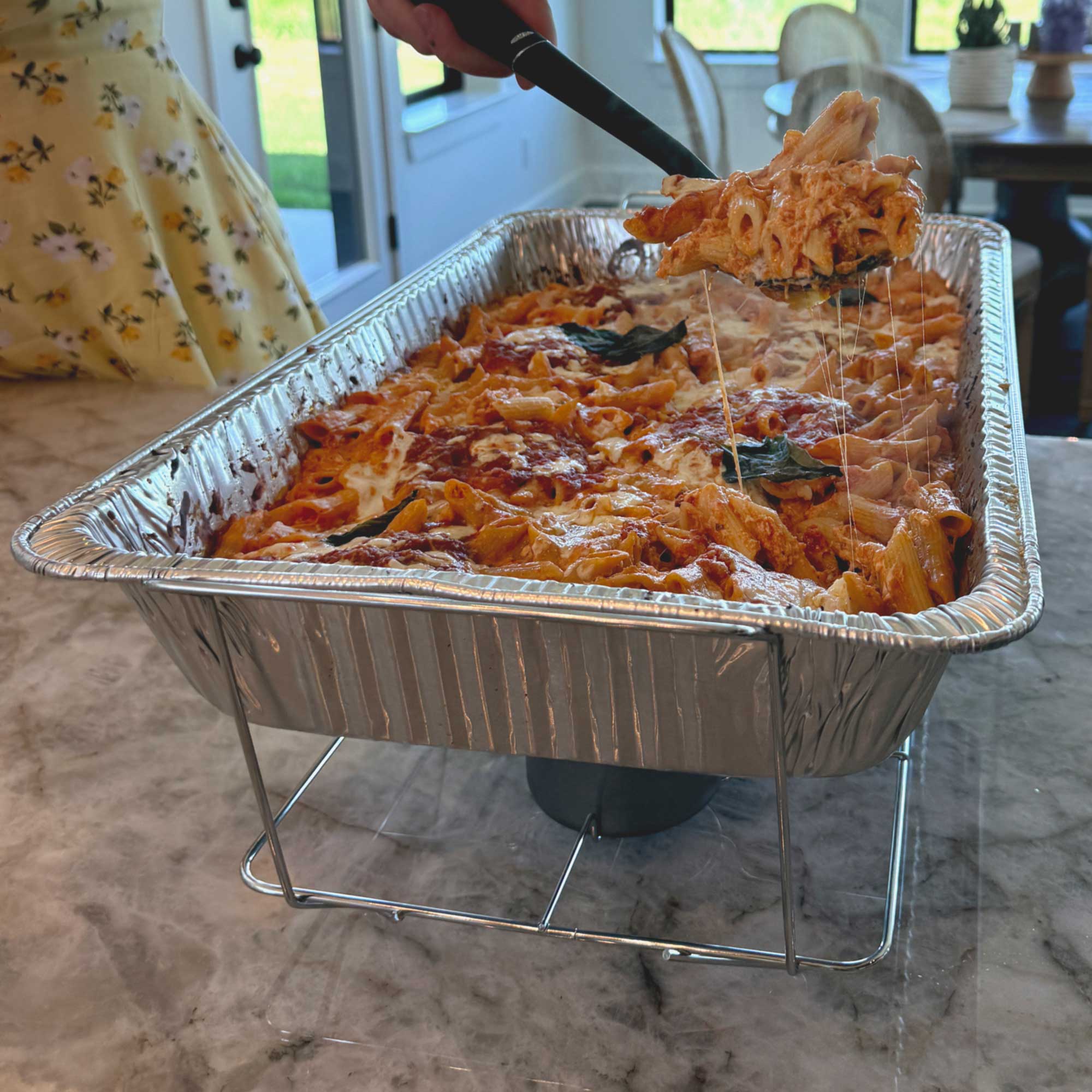 cheesy baked ziti in an aluminum pan, held by our wire frame.
